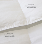 Close-up of a white quilt with text highlighting features like a 100% cotton Japara cover and double-stitched piped edges.