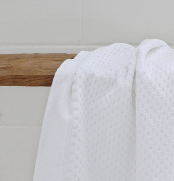 white hotel bathmat hanging on wooden bench