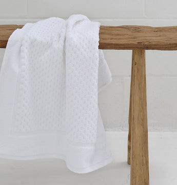 white hotel bathmat hanging on wooden bench